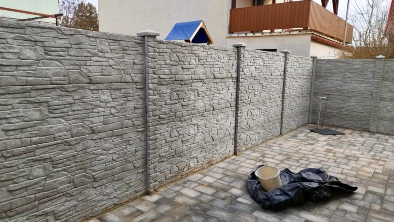 Kőmintás betonkerítés kövezett udvarban